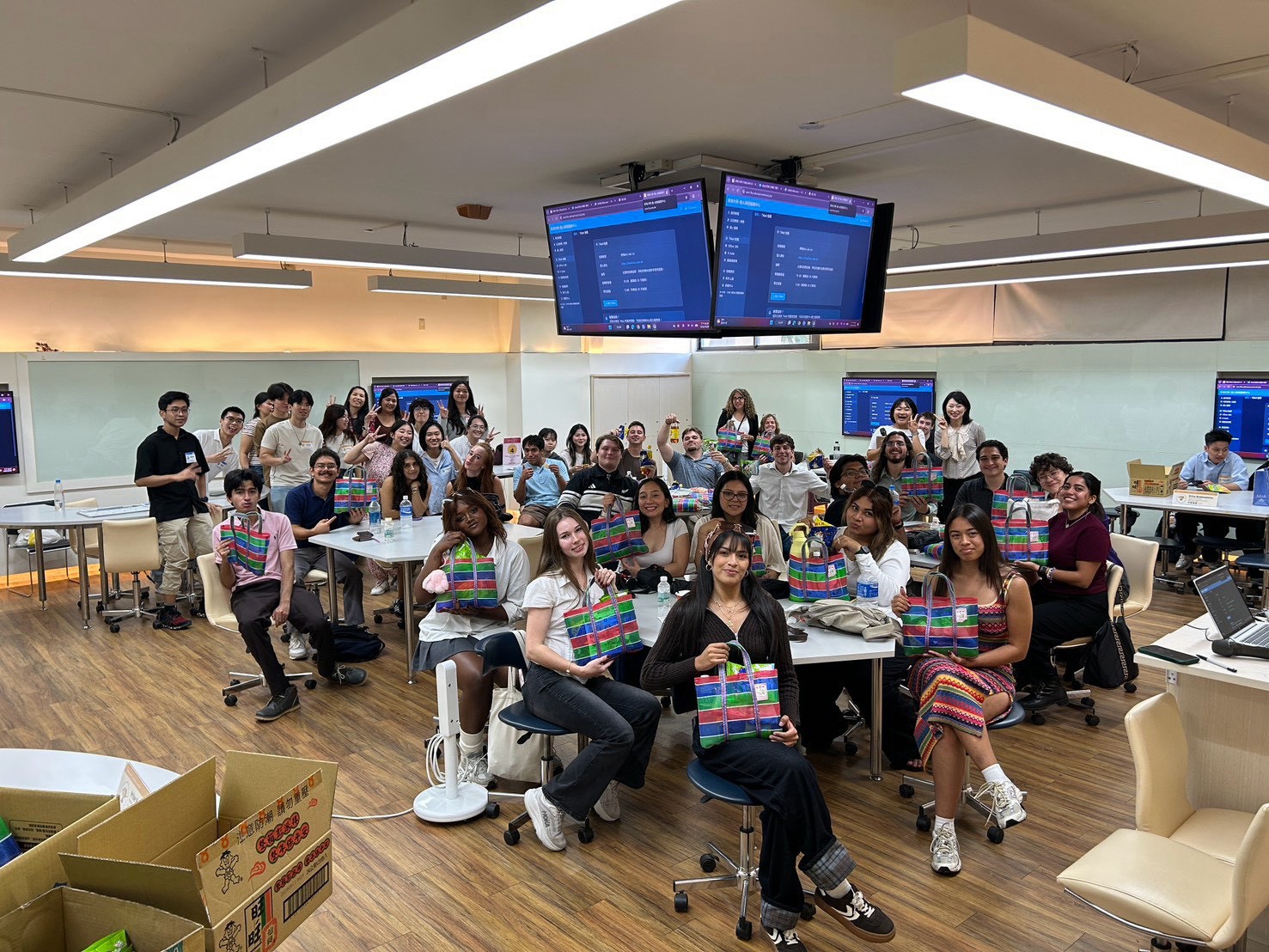 Students from the University of Notre Dame and Holy Cross College pose for a group photo in a Tunghai classroom, holding Taiwanese striped tote bags.